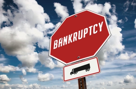 Stop sign that says Bankruptcy and has an attached sign showing a truck