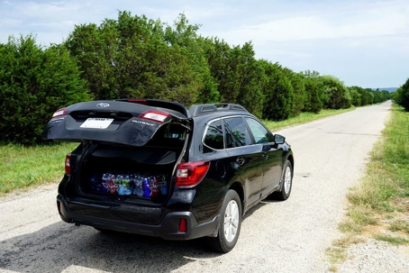 hatch back sedan parked on a dirt road with the trunk open