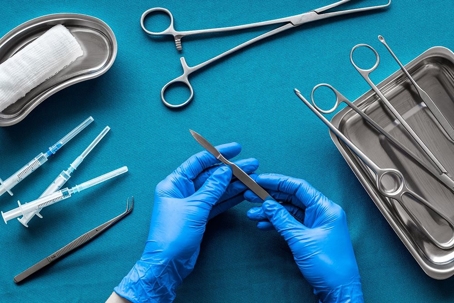 gloved hands holding a surgery tool