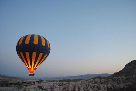 hot air balloon rising over a valley