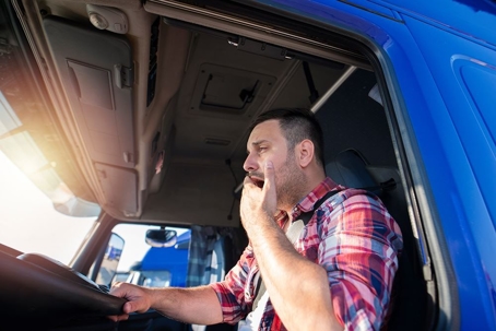 truck driver yawns from behind the steering wheel
