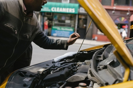 Man looking under hood of a car