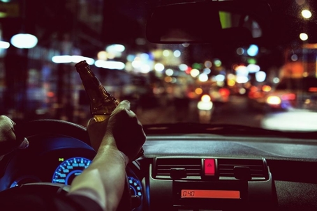 person driving at night while holding a beer