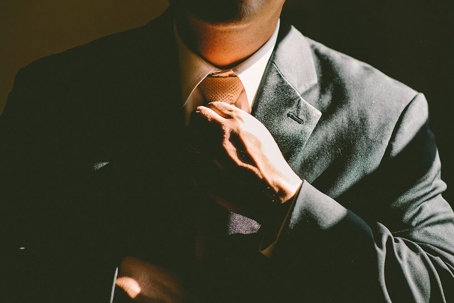man in a suit straightens his tie