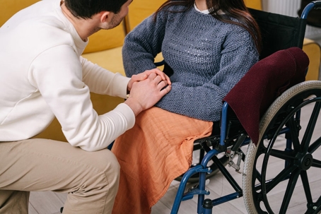 man holding hands and consoling a woman in a wheelchair