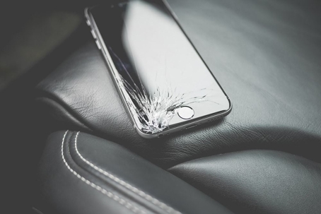cracked iPhone sitting on leather seat